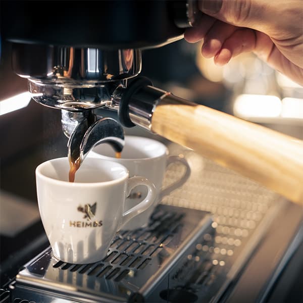 Frisch gebrühter Espresso läuft vom Siebträger in zwei Heimbs Espresso Tassen